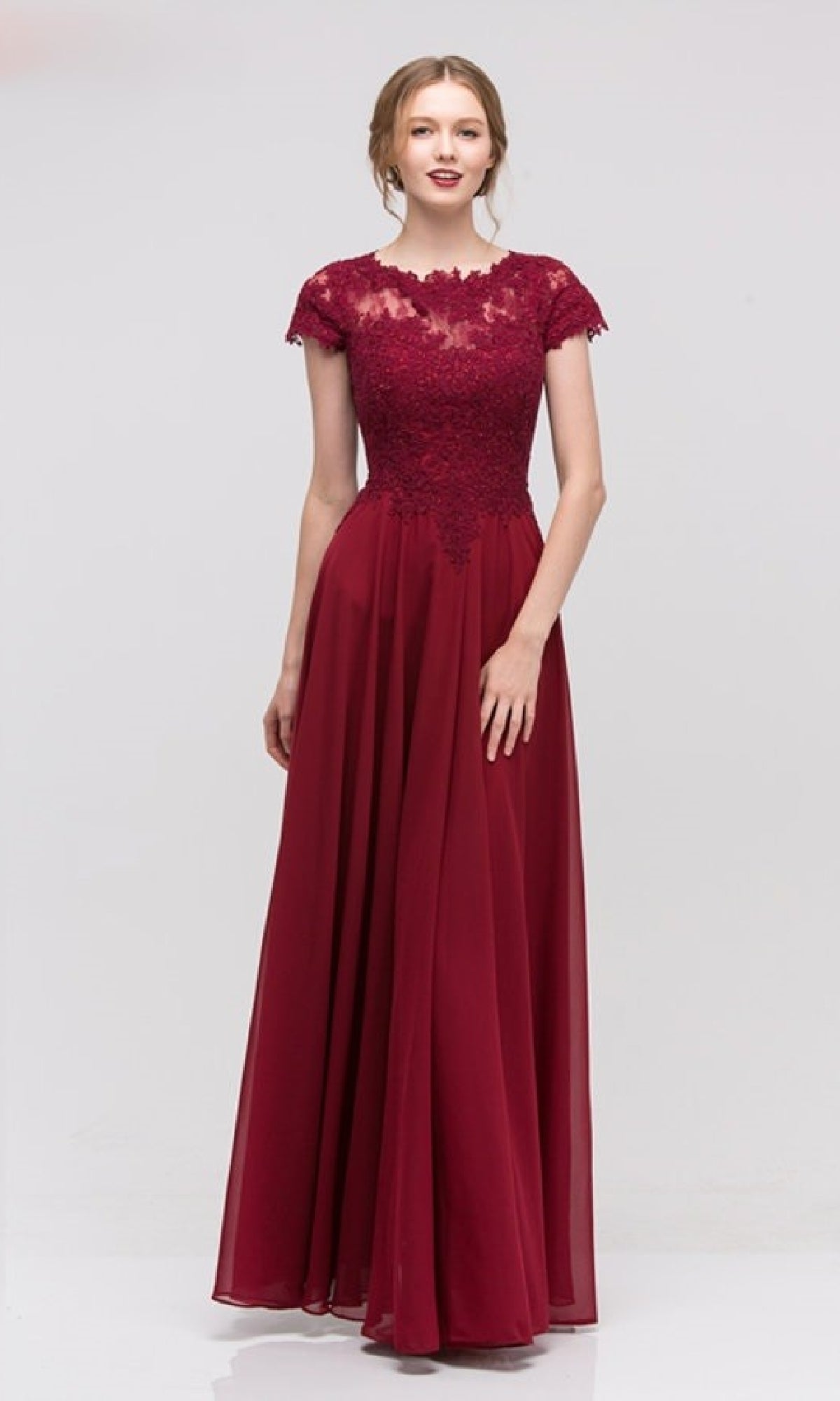 A woman wears the Eureka 4909, a short-sleeve long A-line formal dress featuring an embroidered lace bodice and flowing chiffon skirt in burgundy, beautifully displayed against a plain light background.